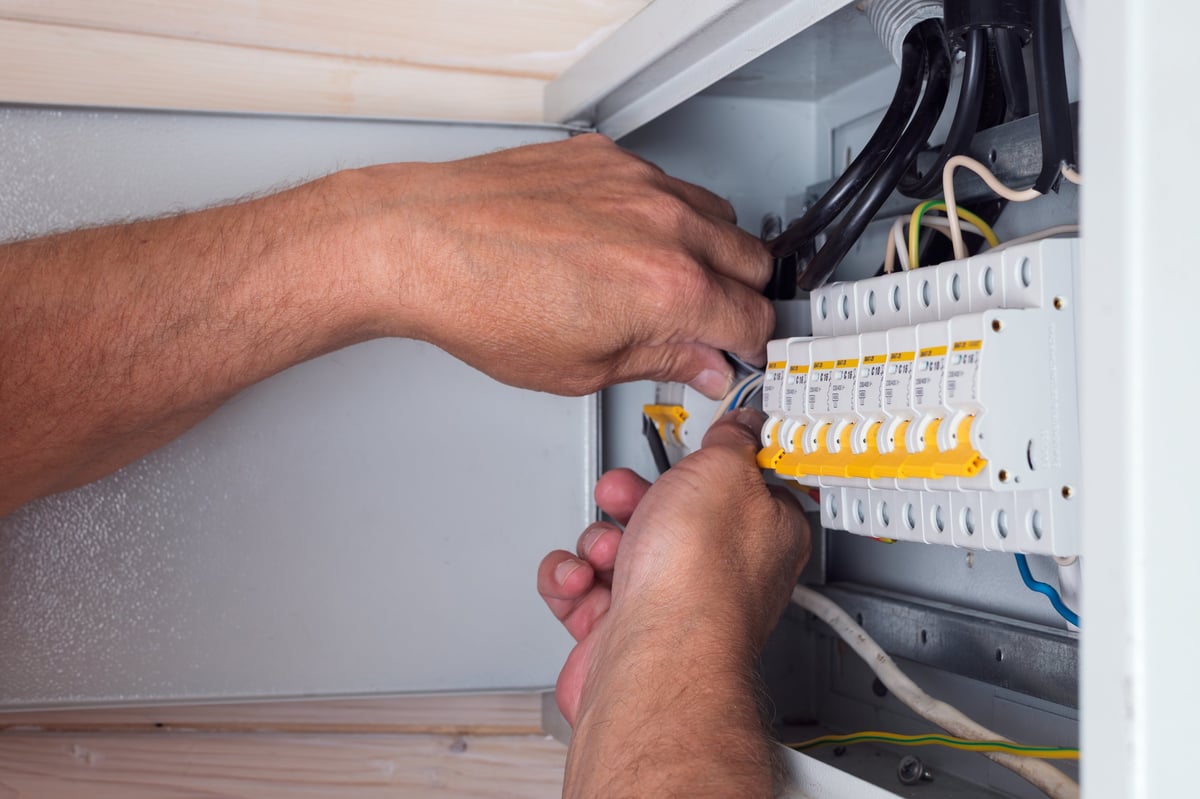 Electrician is using a digital meter to measure the voltage at the power outlet